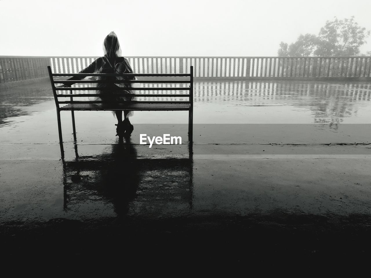 REAR VIEW OF WOMAN STANDING BY RAILING AGAINST SKY