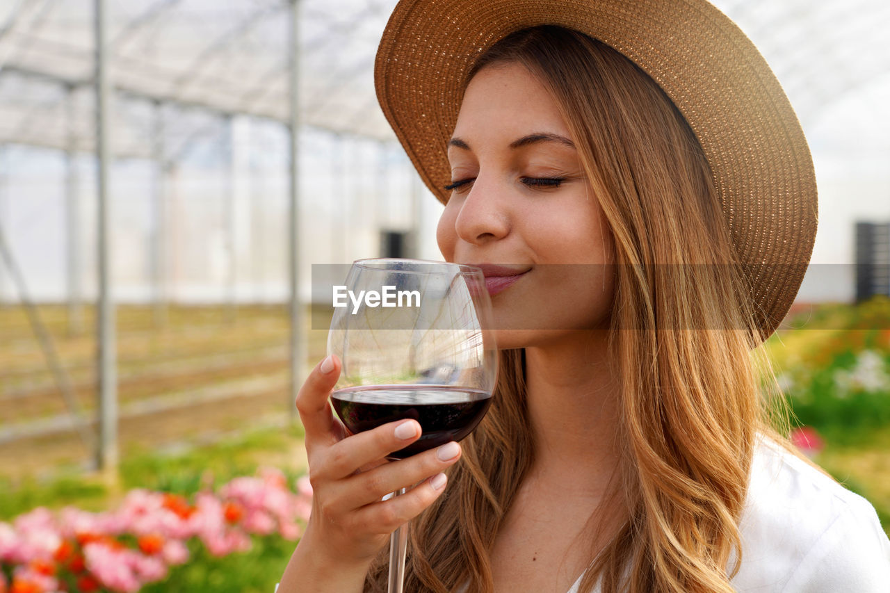 Close-up of beautiful woman smelling red wine from glass with closed eyes