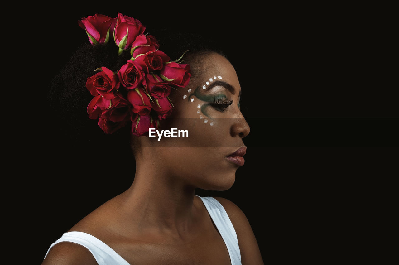 Woman with make-up standing against black background