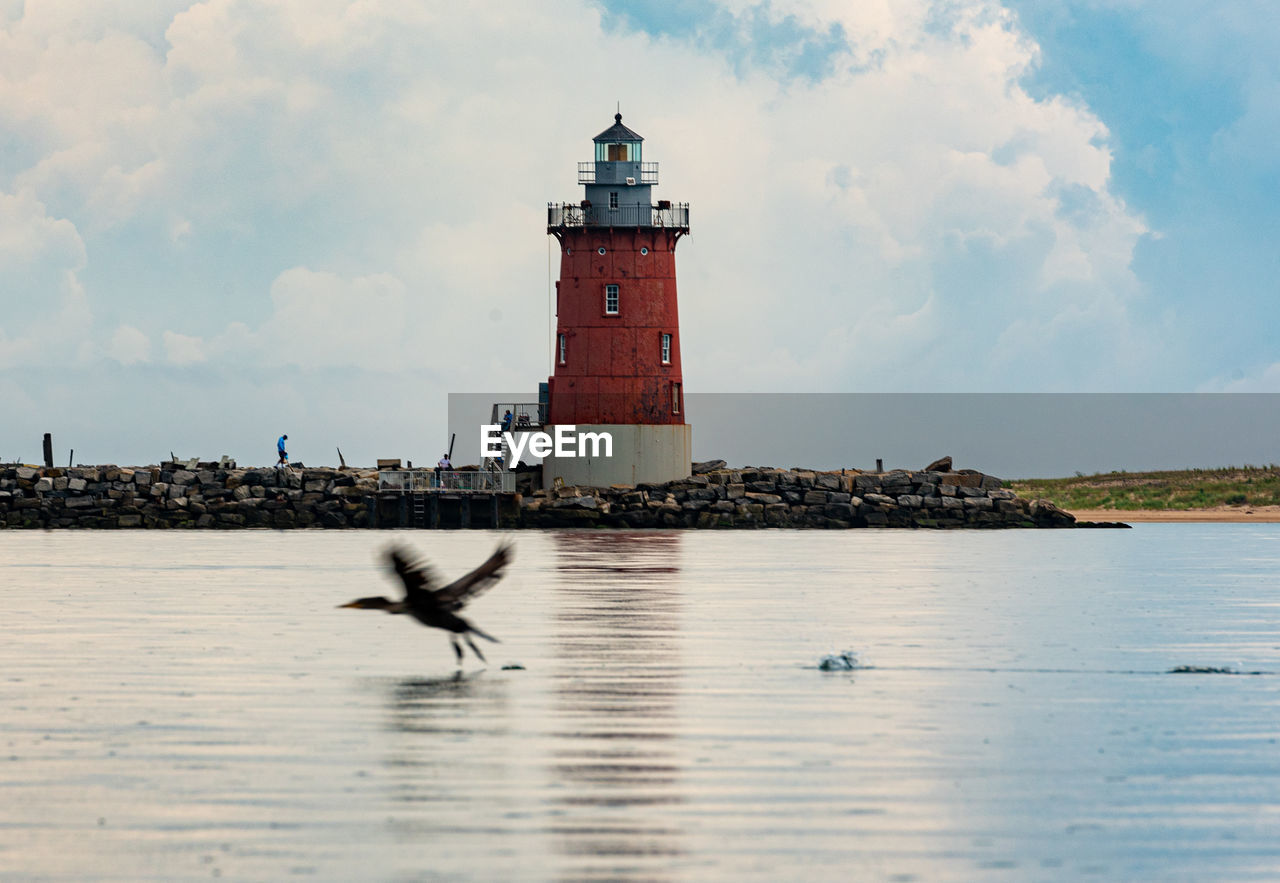 LIGHTHOUSE BY SEA AGAINST SKY AND BUILDINGS