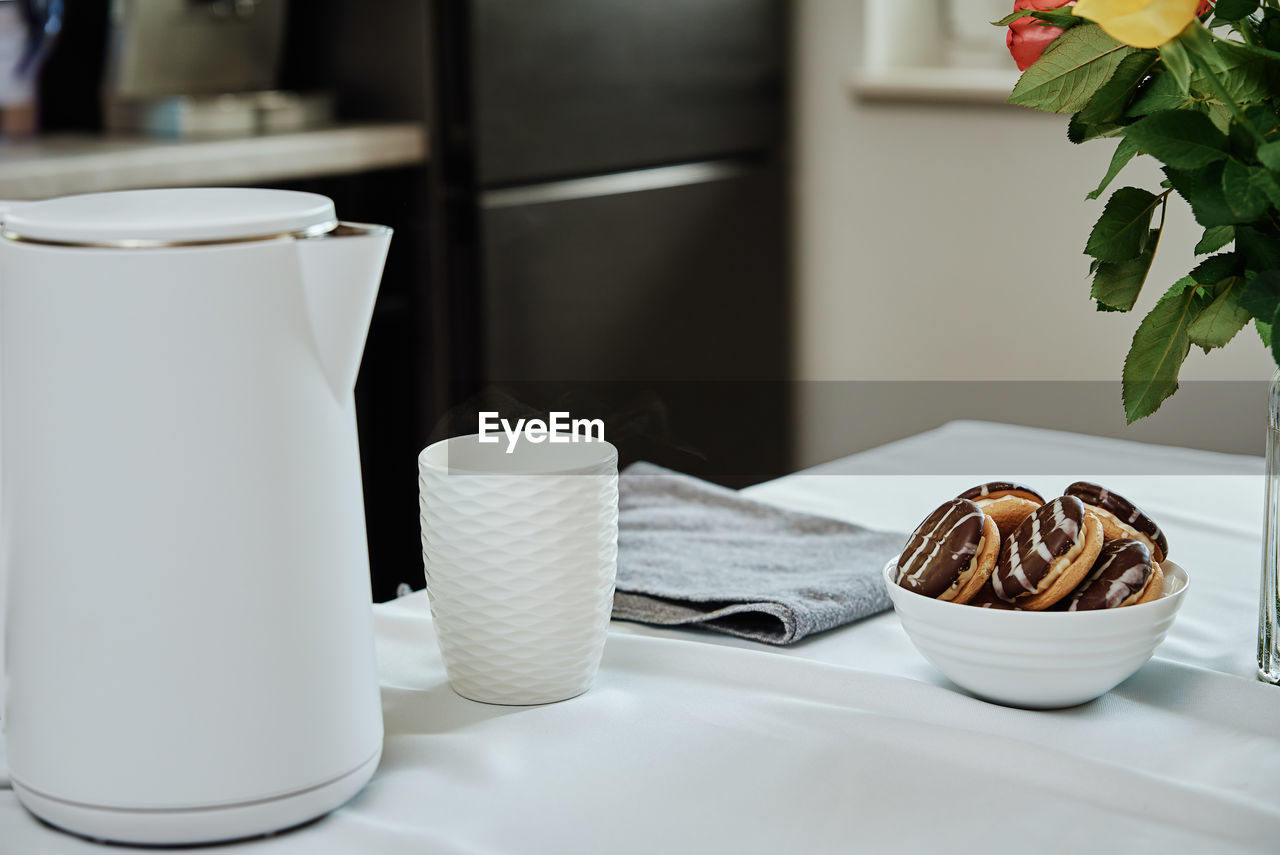 Electric kettle and cup for tea on table