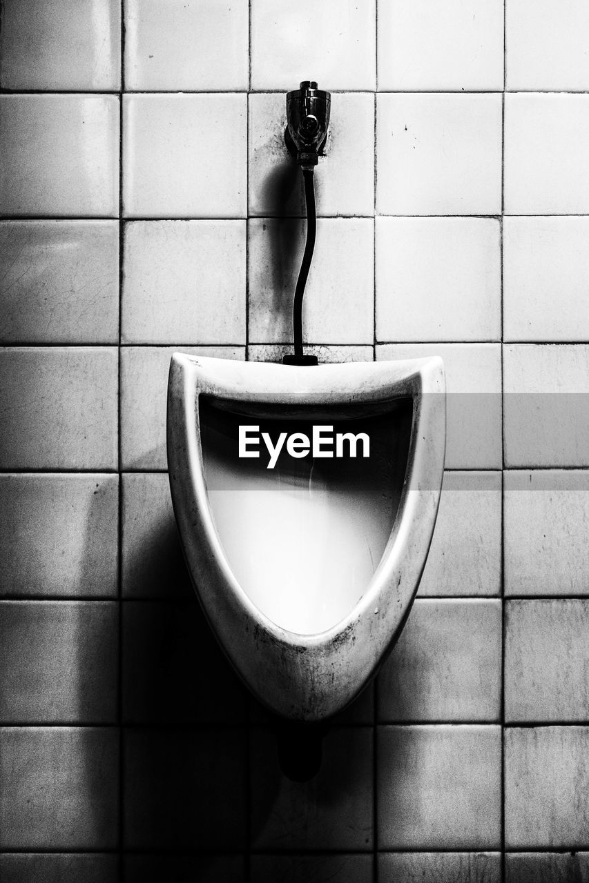 Urinal on wall in bathroom
