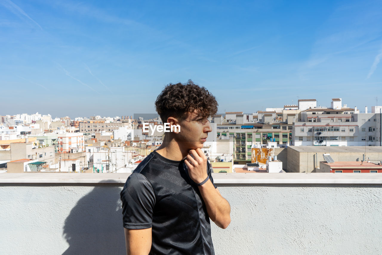 FULL LENGTH OF YOUNG MAN STANDING IN CITY AGAINST SKY