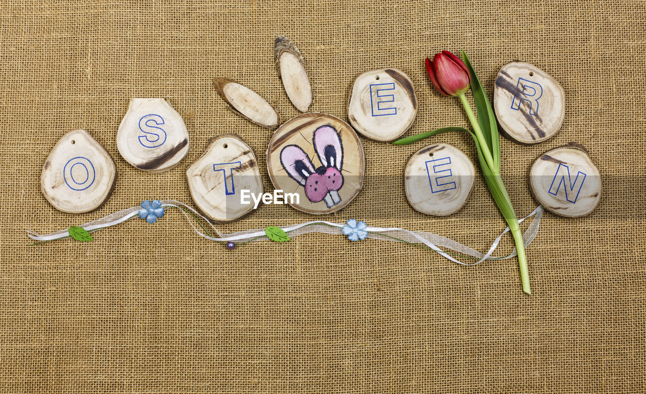 Directly above view of rabbit head with alphabets and tulip on jute