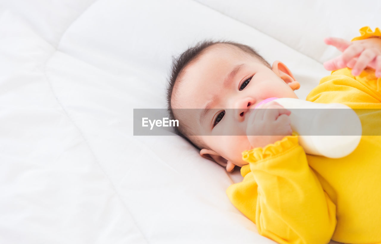 High angle portrait of baby girl lying on bed