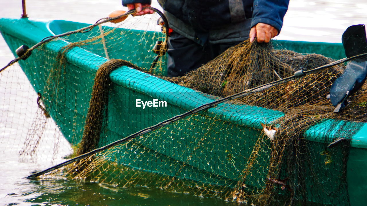 Midsection of fisherman fishing on boat in sea