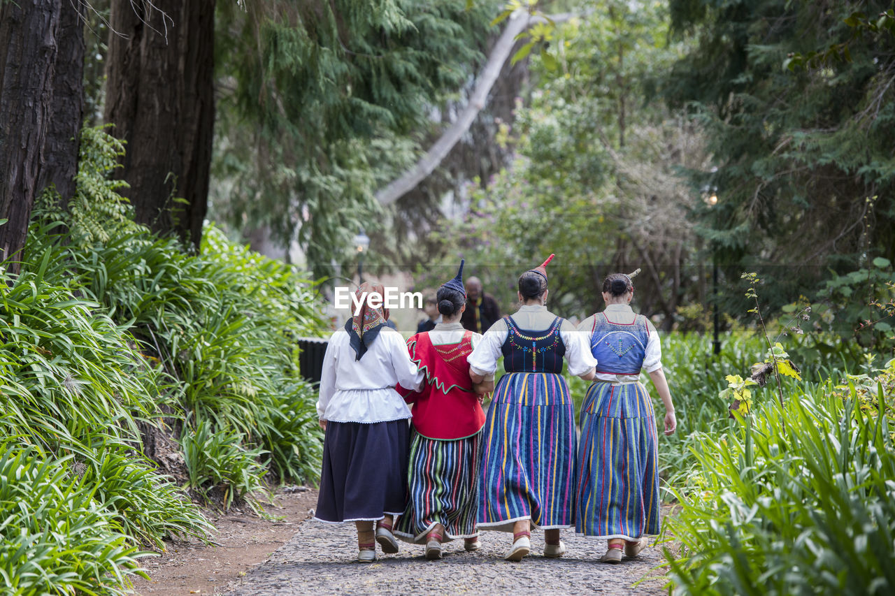 REAR VIEW OF PEOPLE STANDING BY THE FOREST