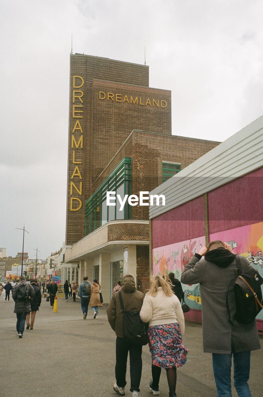 GROUP OF PEOPLE WALKING IN FRONT OF BUILDING