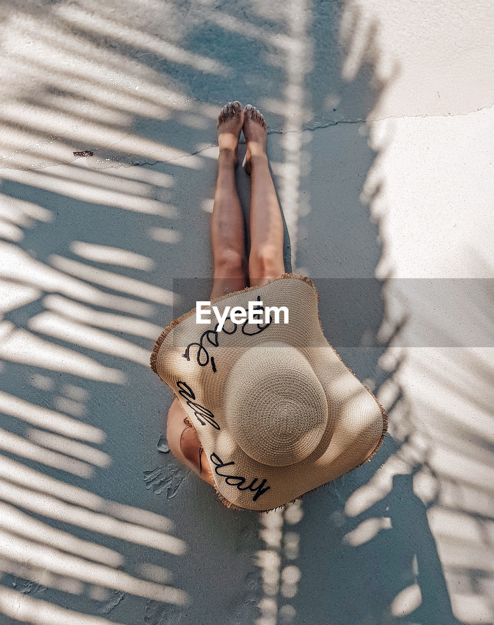 Overhead view of woman with summer hat on sandy beach, tropical, vacations, leisure, palm leaf.