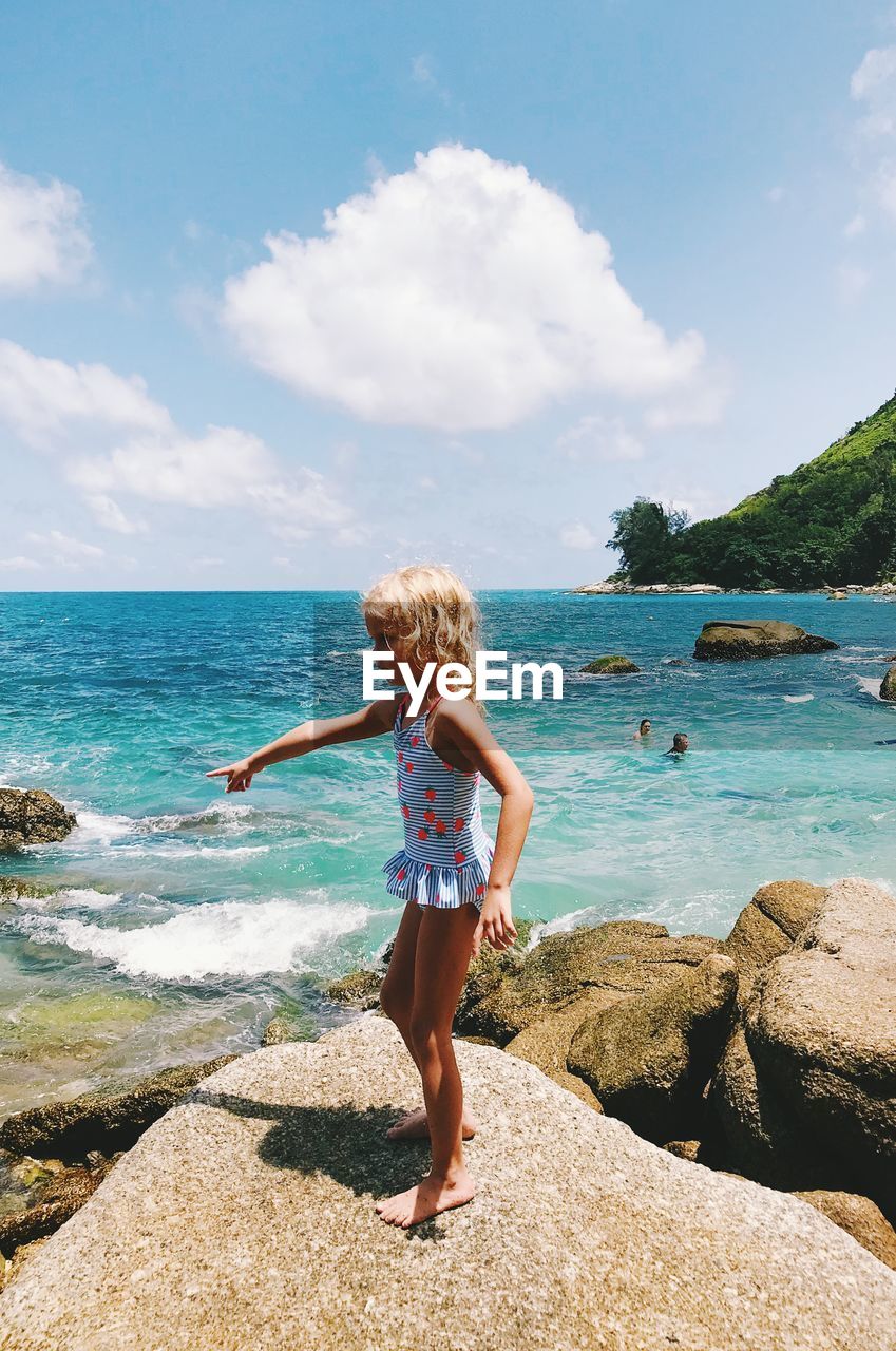 Side view of girl standing on rock at beach