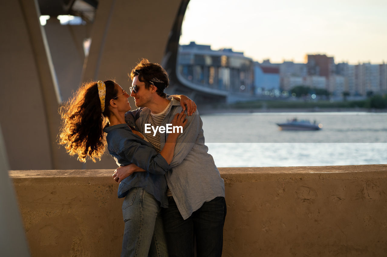 Two lovers kiss at sunset. happy stylish couple embrace. lovely young man and woman hug in sunlight