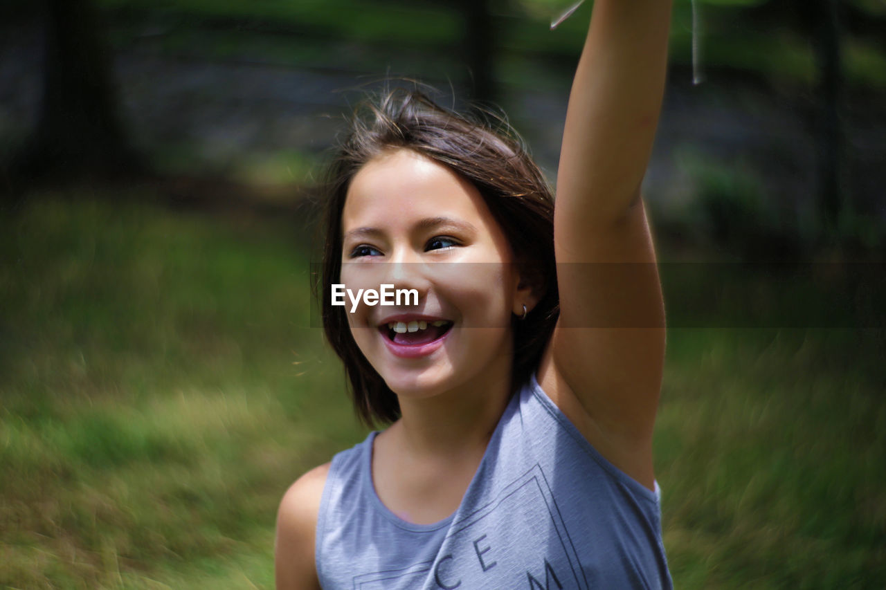 Close-up of happy girl with arm raised standing on field