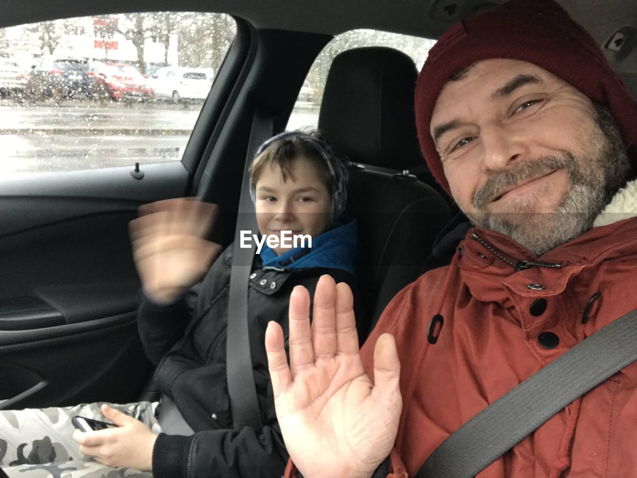 Portrait of smiling man and son gesturing while sitting in car