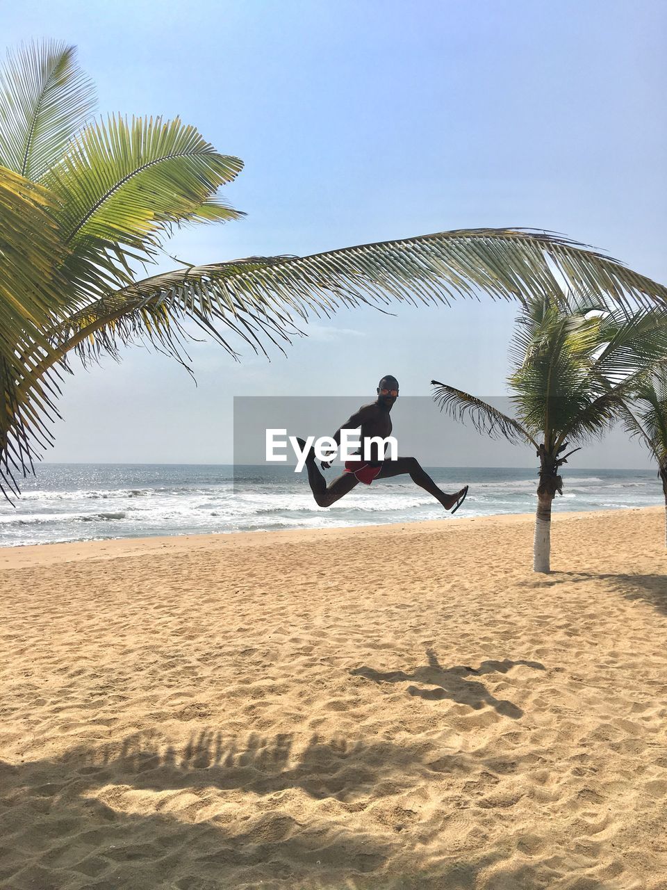 Portrait of man jumping at beach against sky