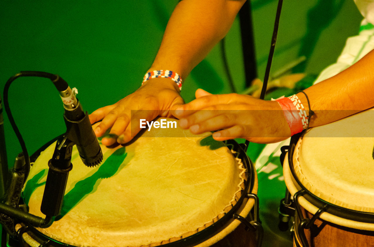 music, drum, arts culture and entertainment, membranophone, percussion, hand, musical instrument, drum - percussion instrument, musical equipment, yellow, adult, performance, drummer, musician, person, hand drum, green, drums, event, percussion instrument, midsection, one person, close-up, skill, women, holding, indoors