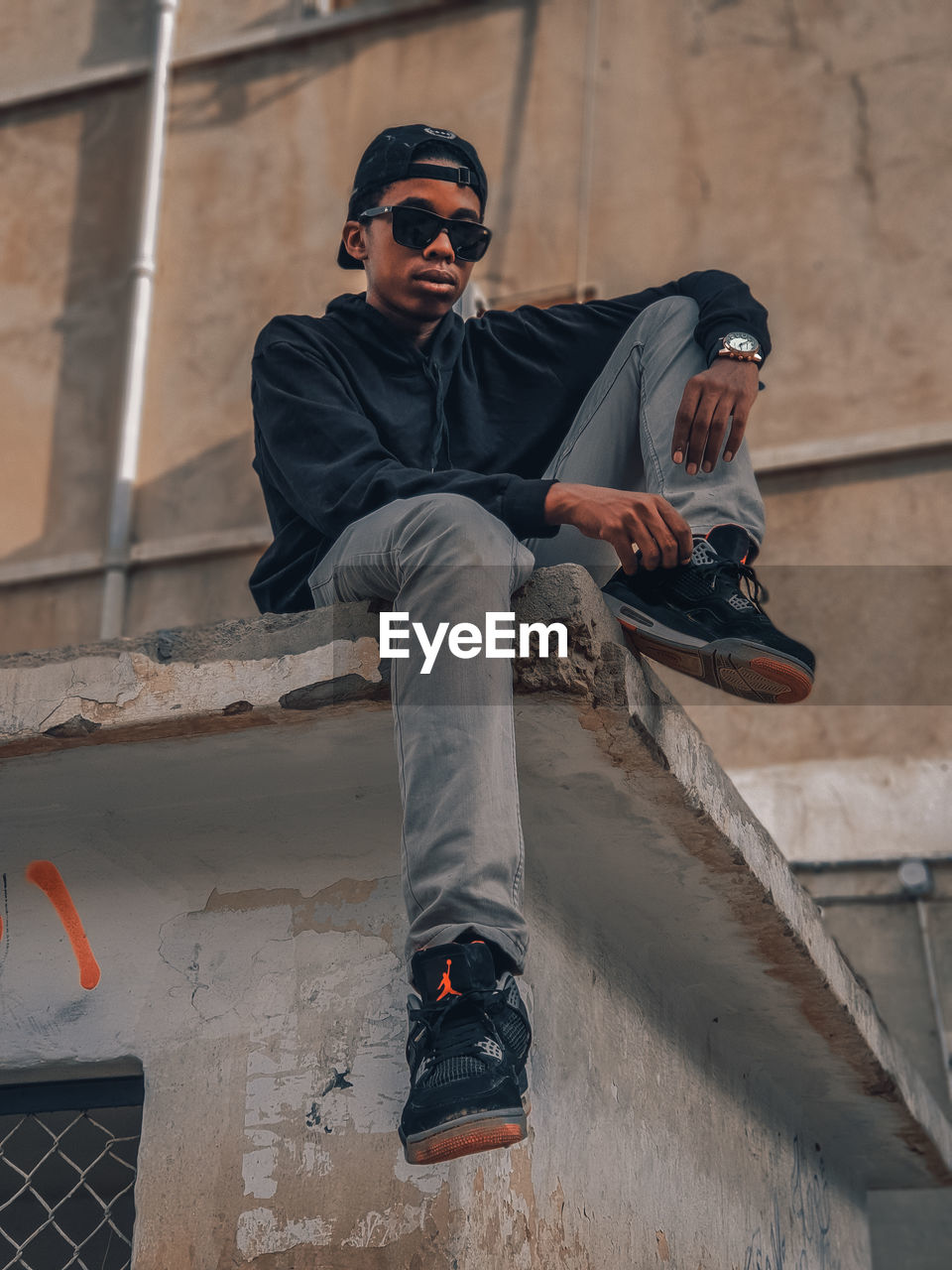 FULL LENGTH OF YOUNG MAN SITTING IN SUNGLASSES