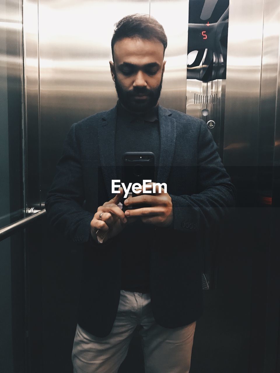 Portrait of man taking selfie while standing at elevator
