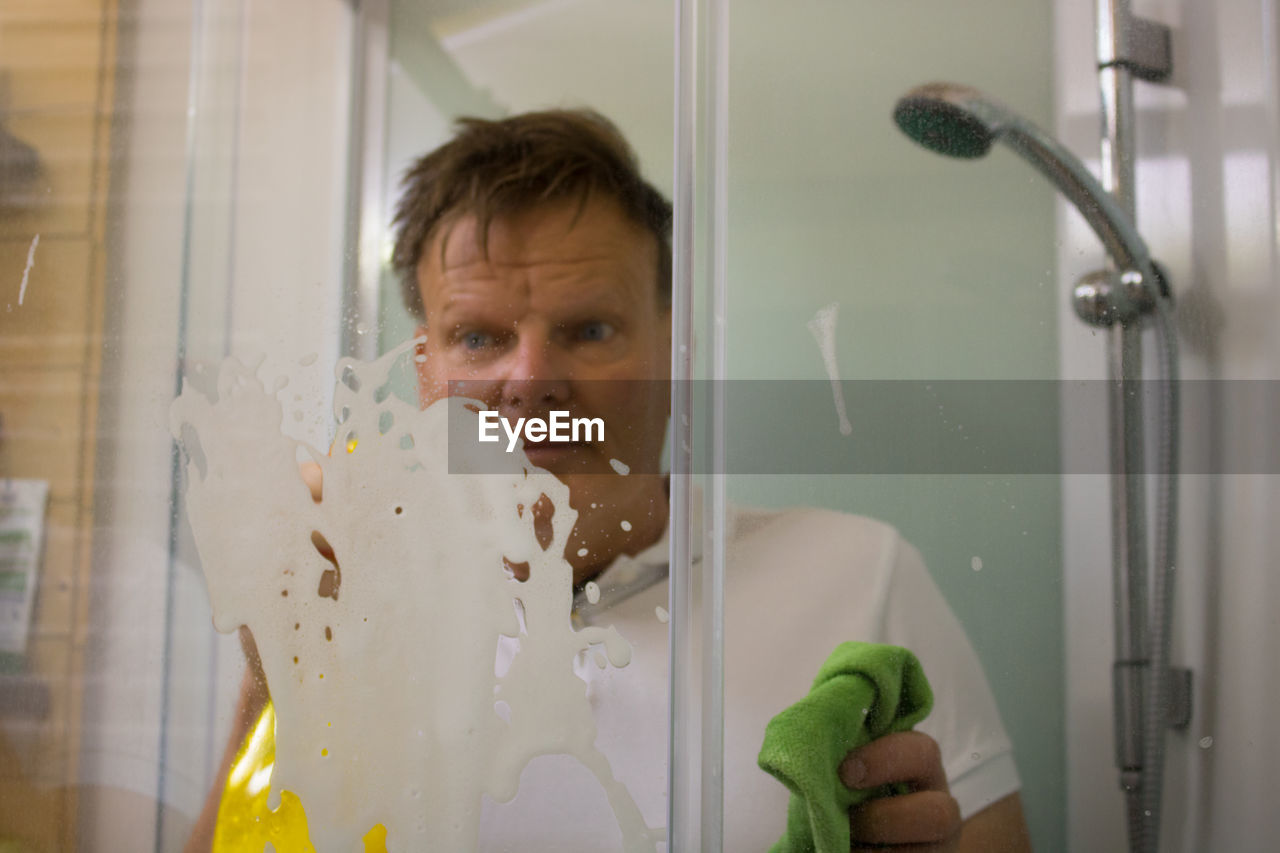 Mature man cleaning bathroom glass