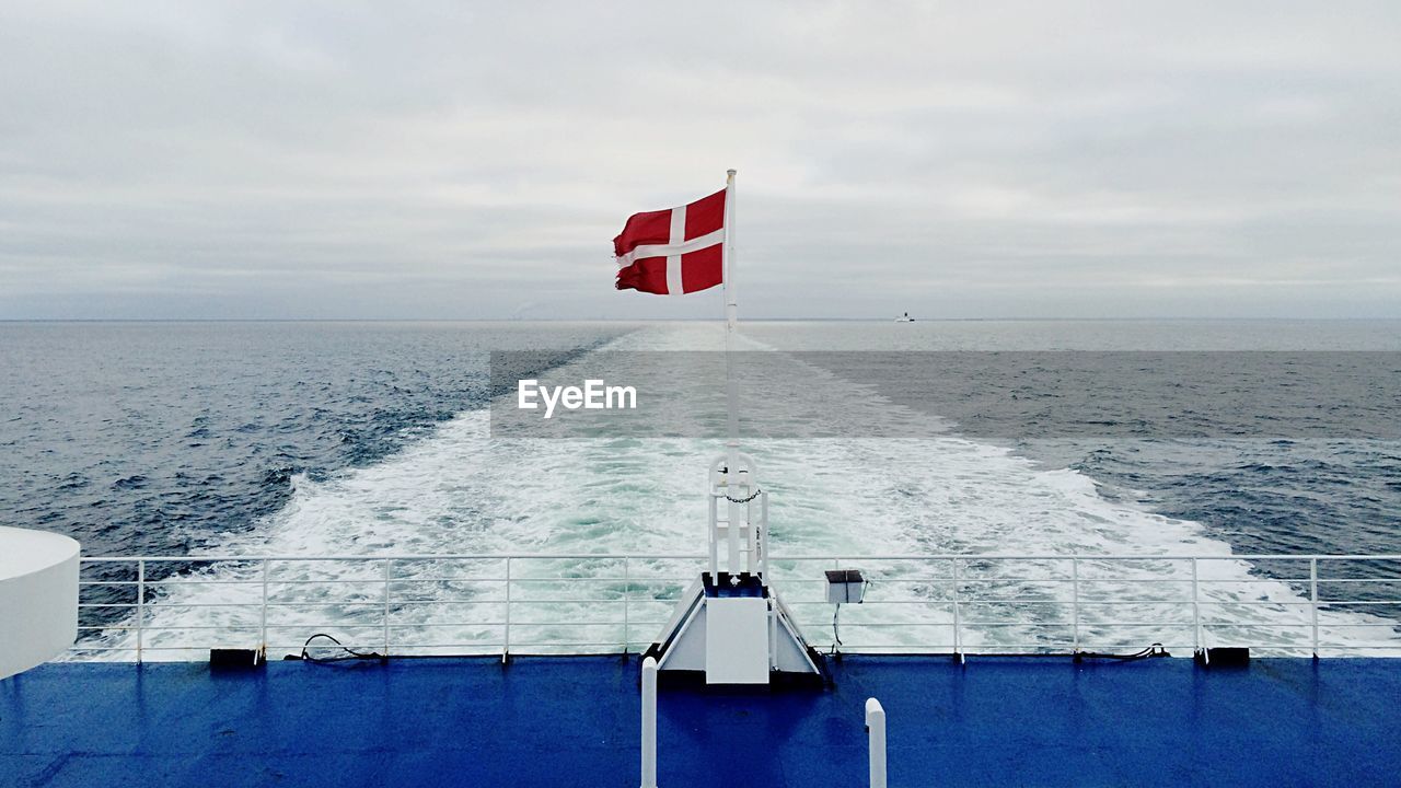 Danish flag waving on boat sailing in sea