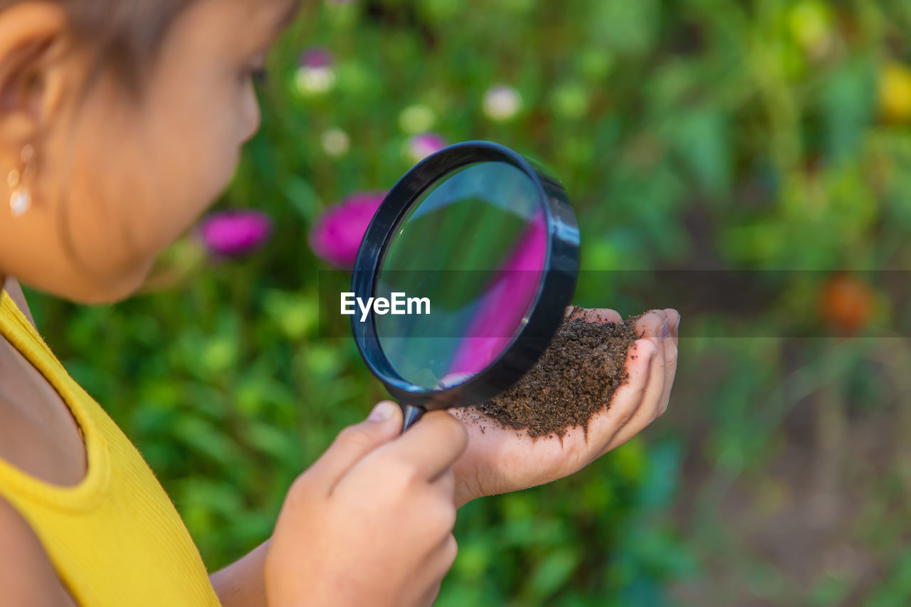 cropped hand of person holding magnifying glass