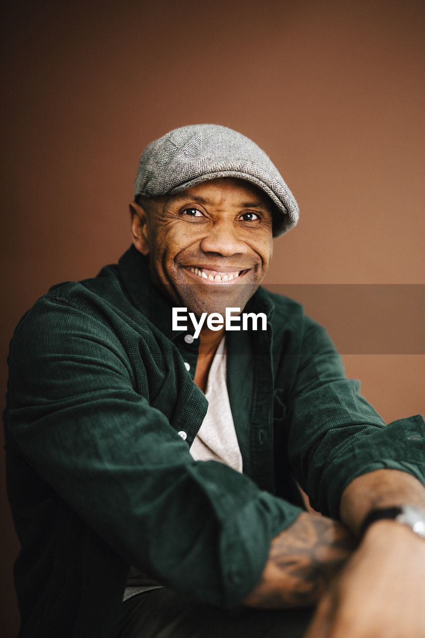 Portrait of happy mature man against brown background