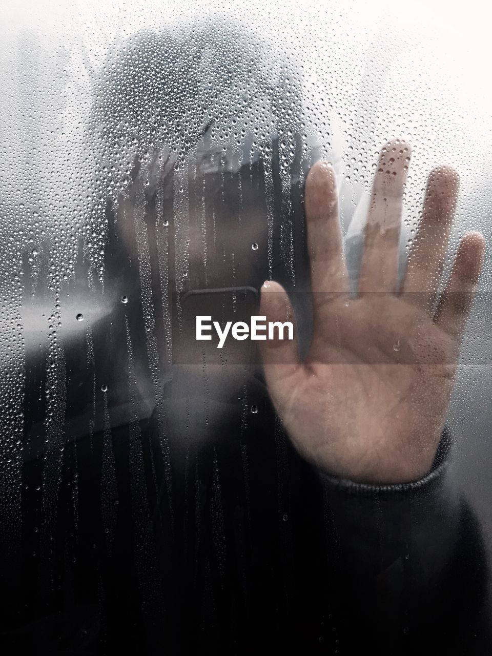 Woman seen through wet window in rainy season