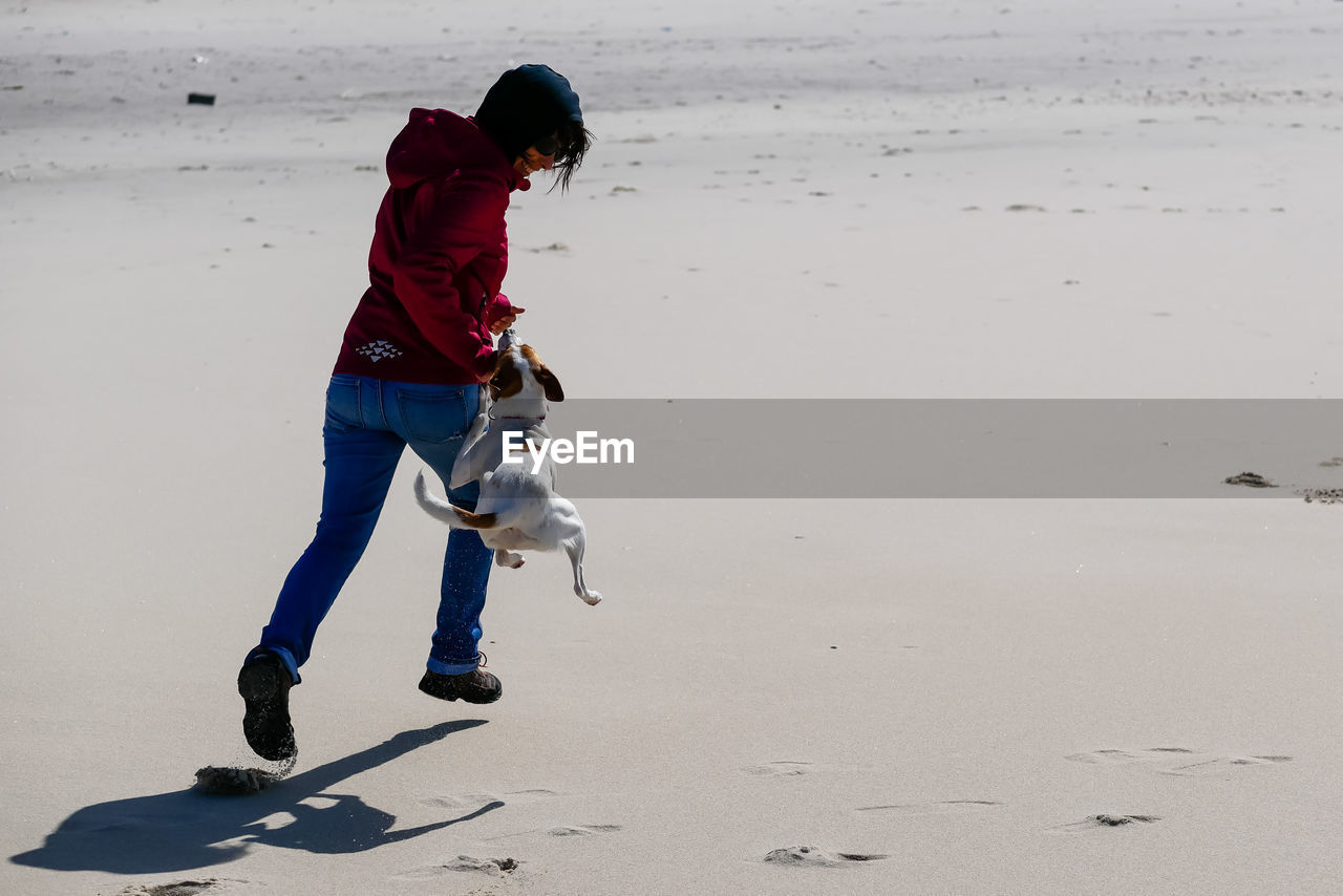 Full length of woman playing with dog outdoors