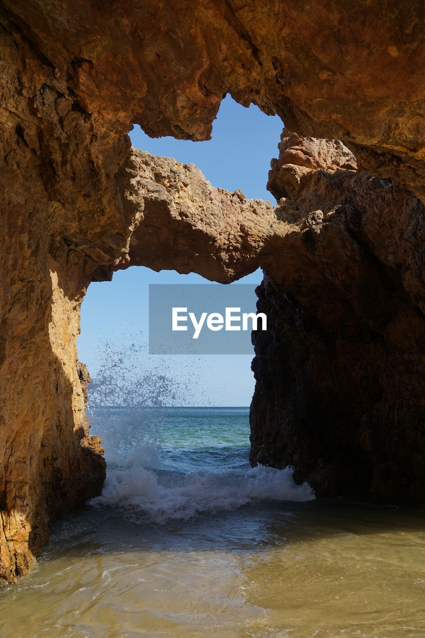 Rock formation on beach against sky