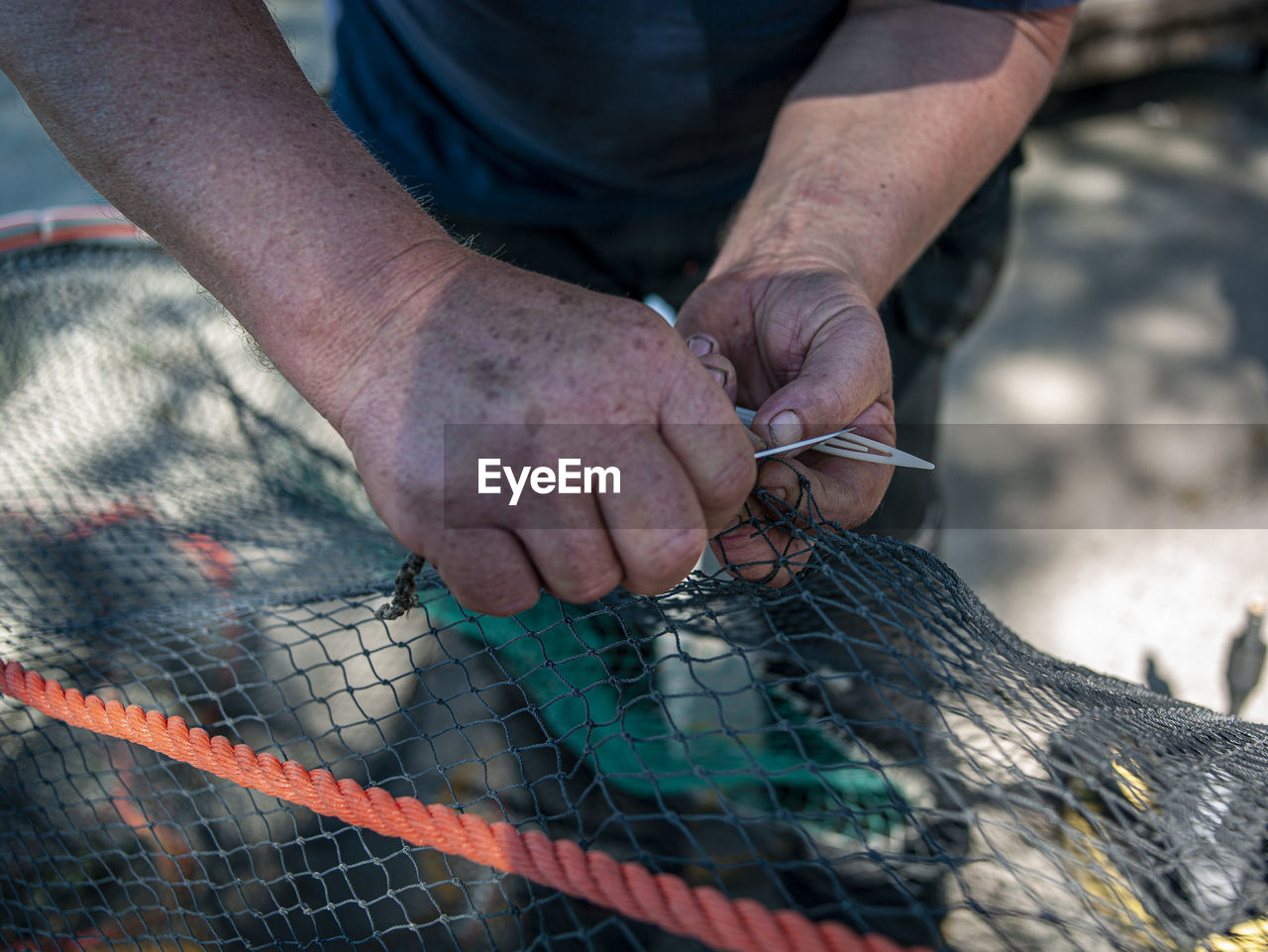 Close-up of man working with fishing net