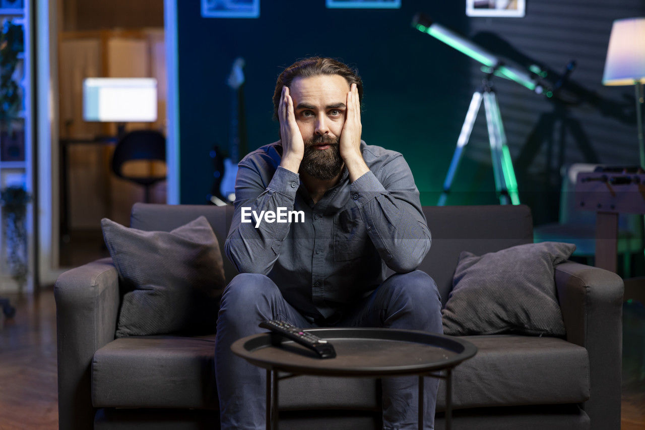 young man using mobile phone while sitting at home