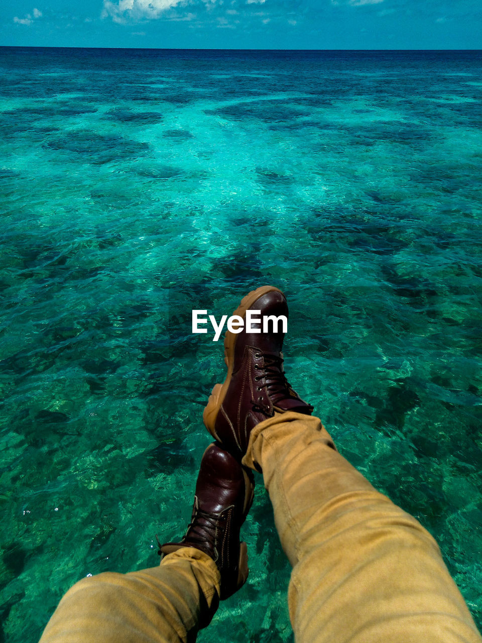 Low section of man sitting by sea