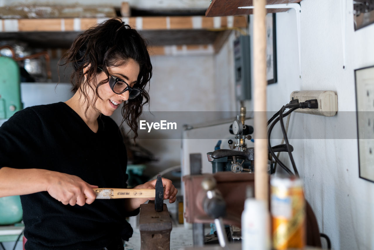 Women works with hammer and anvil in artist studio