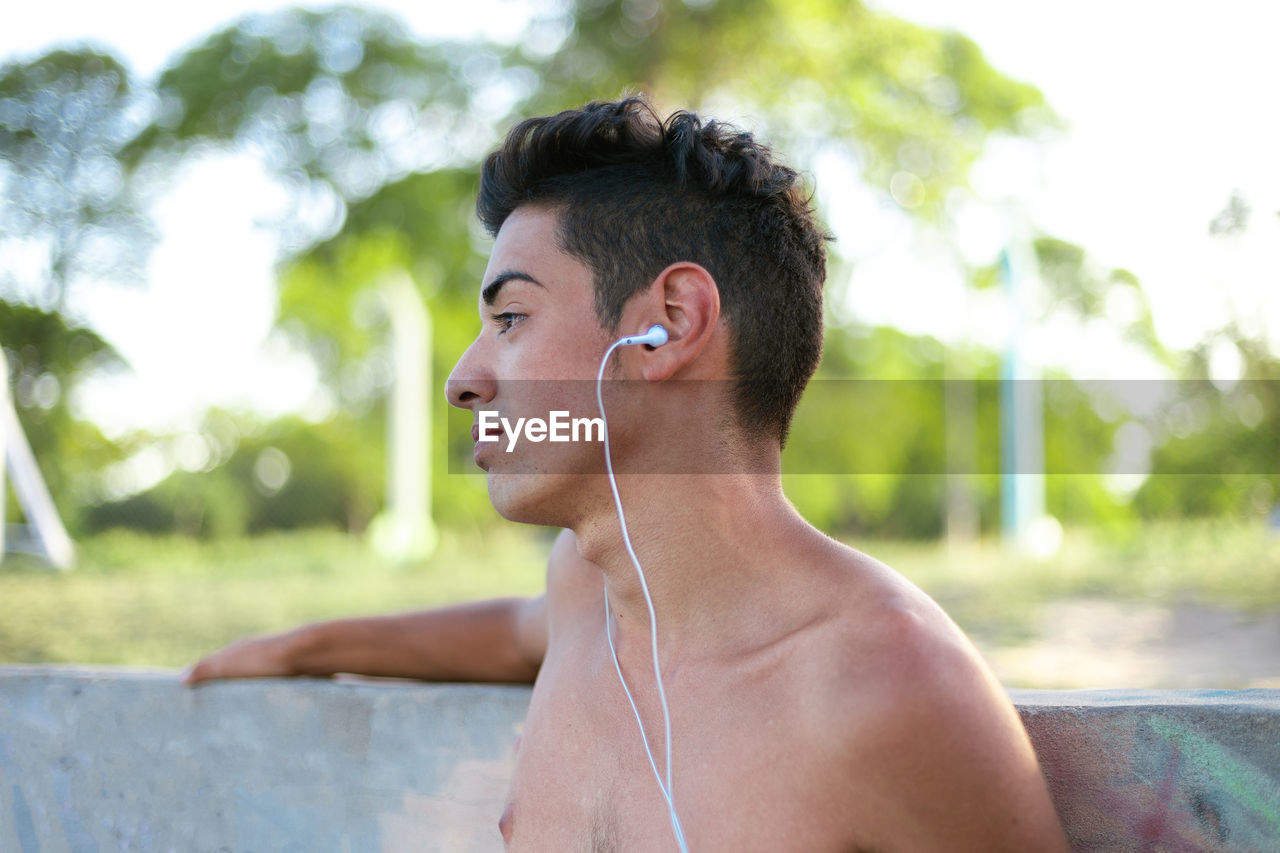 Side viewq of a teenager boy listening to music with earphones