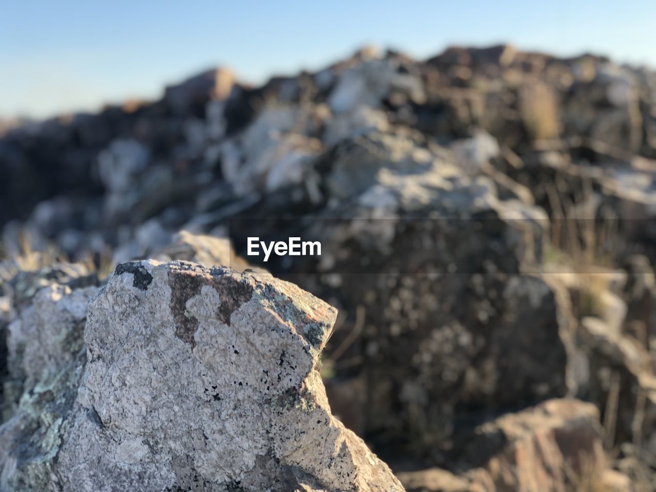 CLOSE-UP OF ROCK AGAINST SKY DURING SUNNY DAY