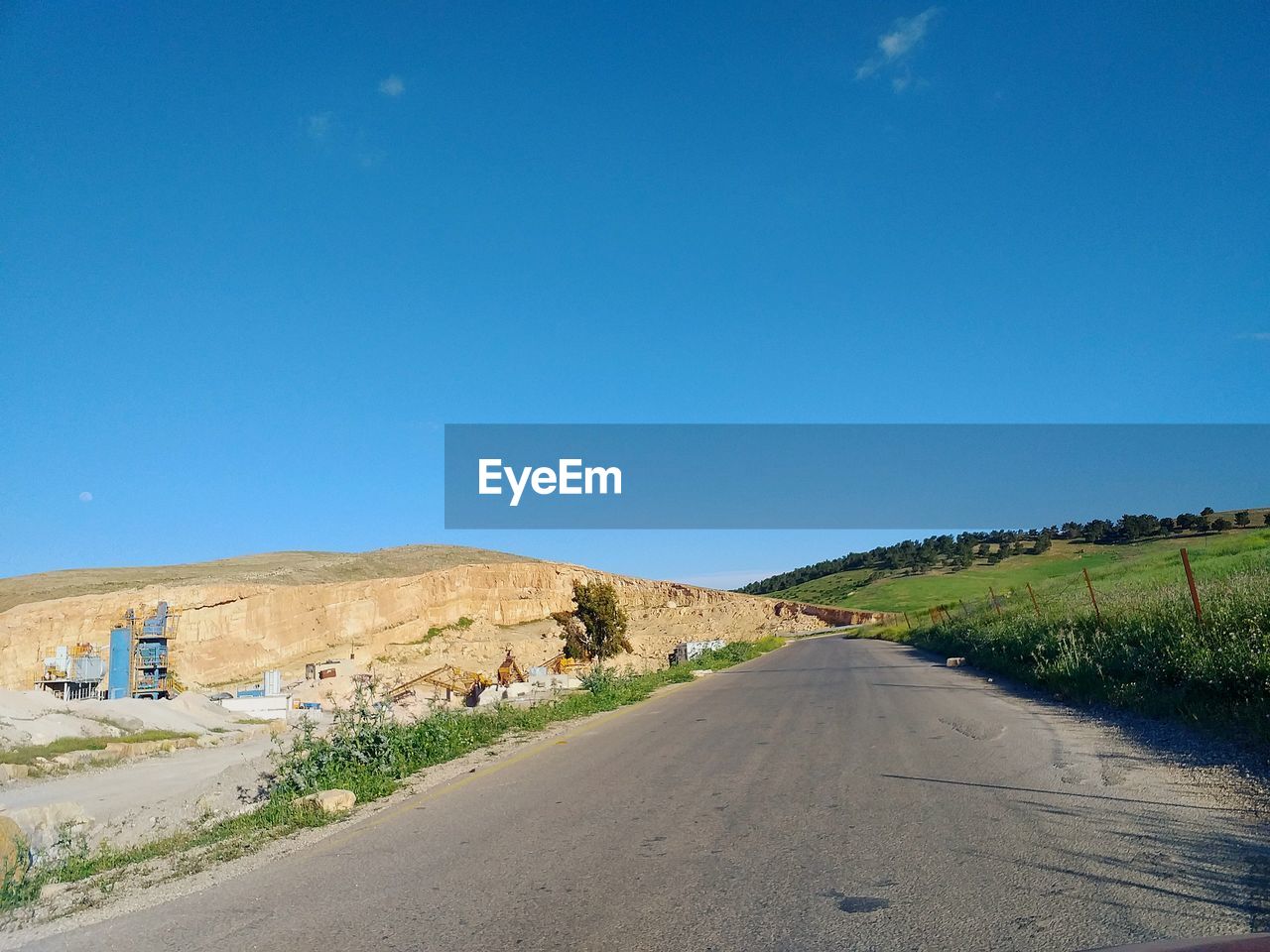 ROAD AMIDST LAND AGAINST BLUE SKY