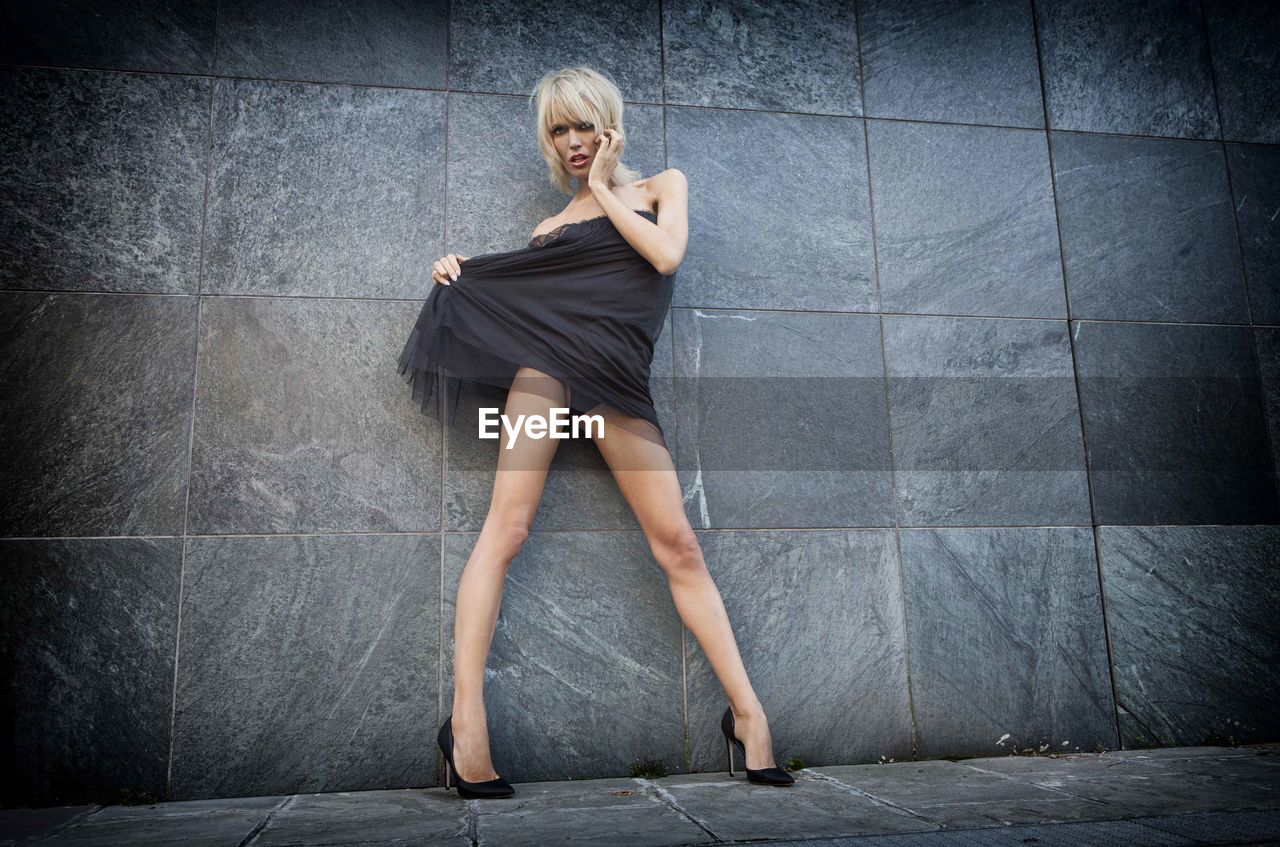 Full length portrait of woman posing against wall