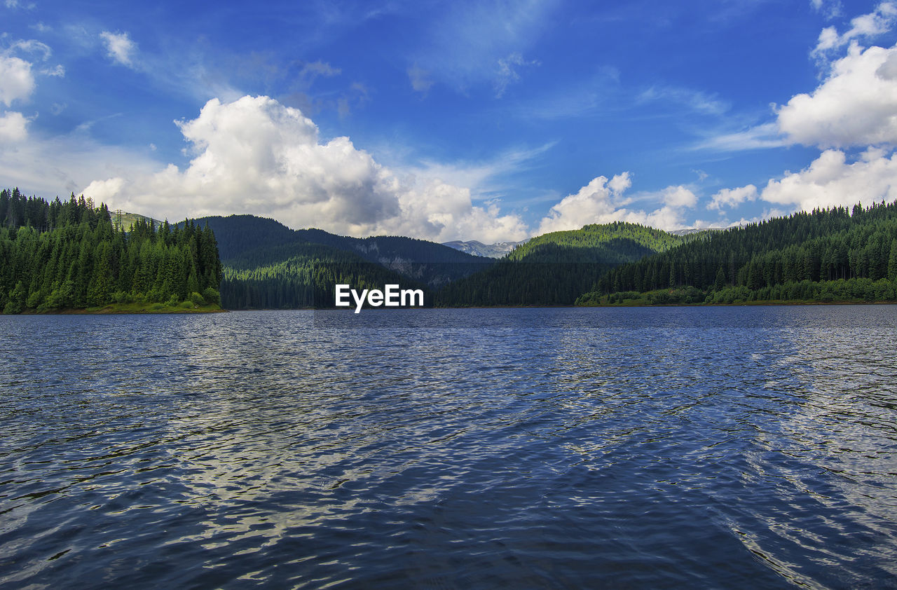 Scenic view of lake by mountains against sky