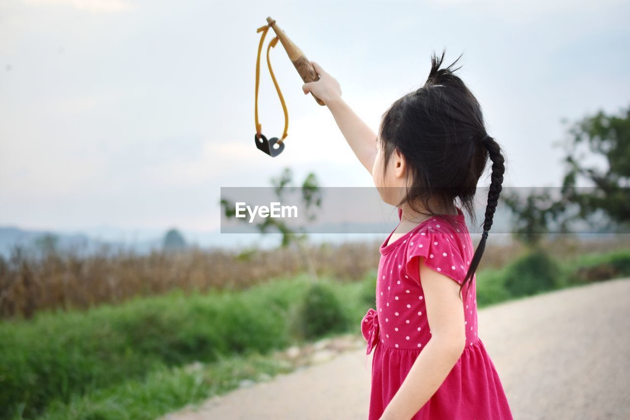 FULL LENGTH OF GIRL HOLDING PLANT ON FIELD