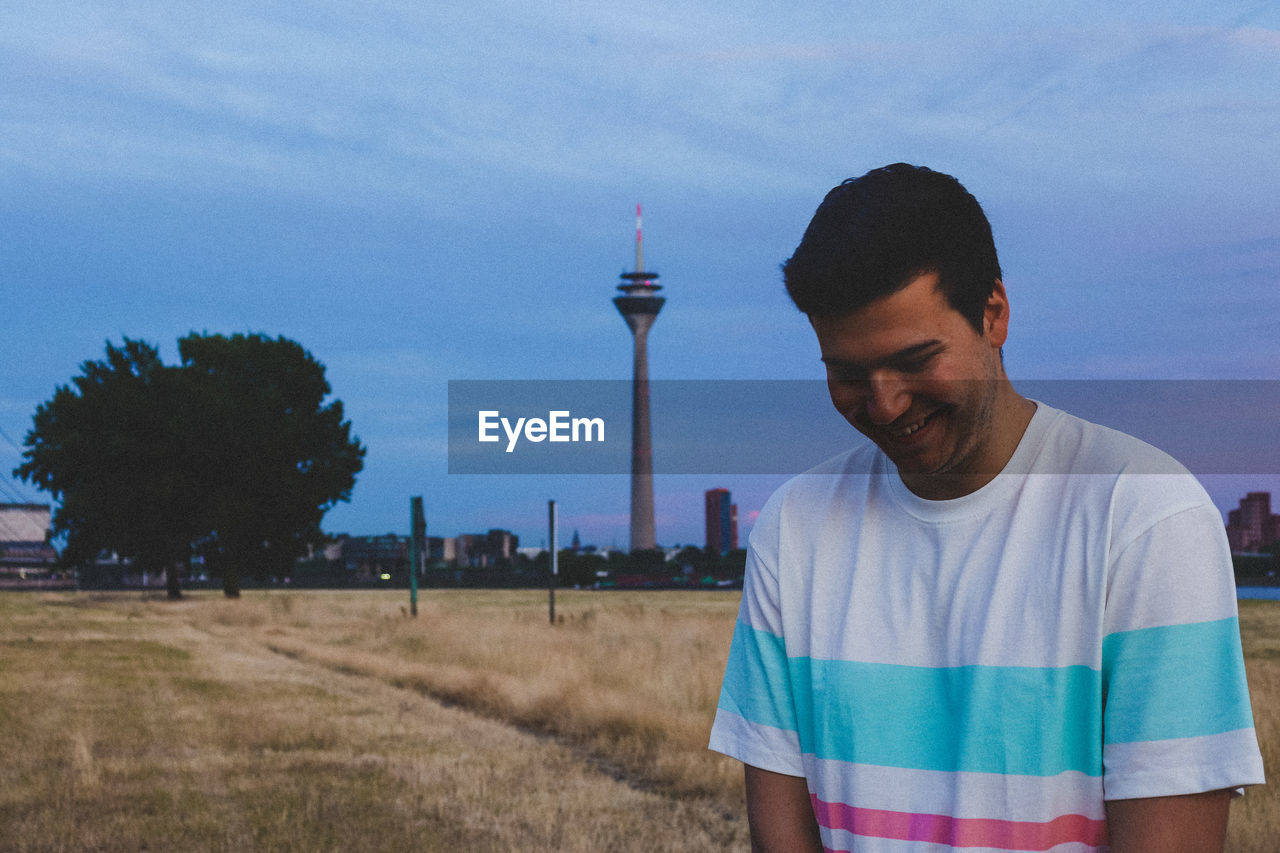 Smiling man standing on field against sky