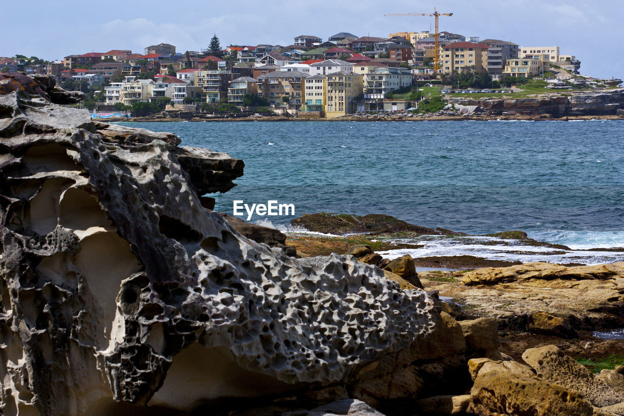 Close-up of sea by cityscape against sky