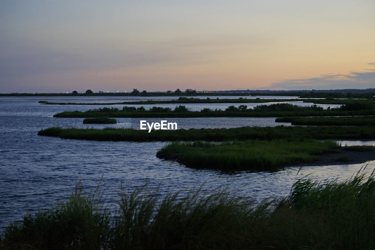 Scenic view of river against sky at sunset