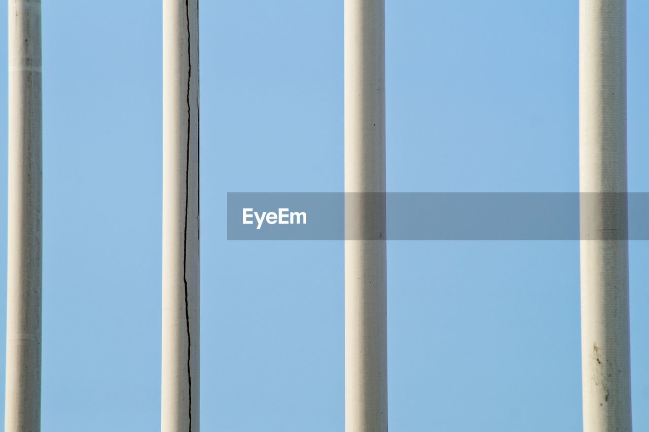 Clear blue sky seen through fence