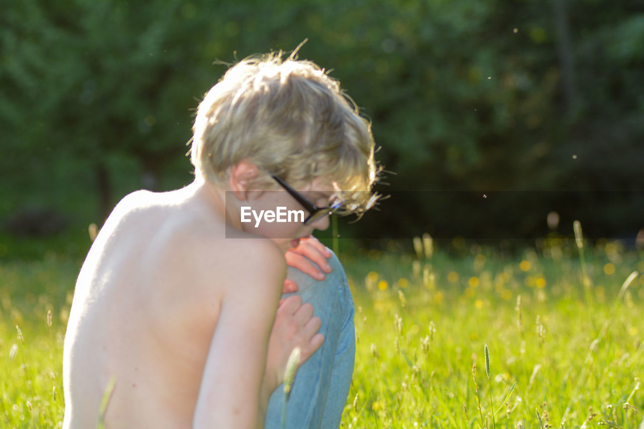 Midsection of shirtless boy on field