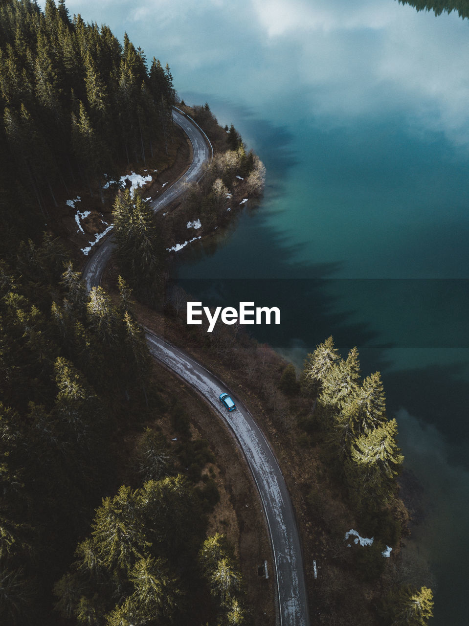 Aerial view of road amidst trees by sea