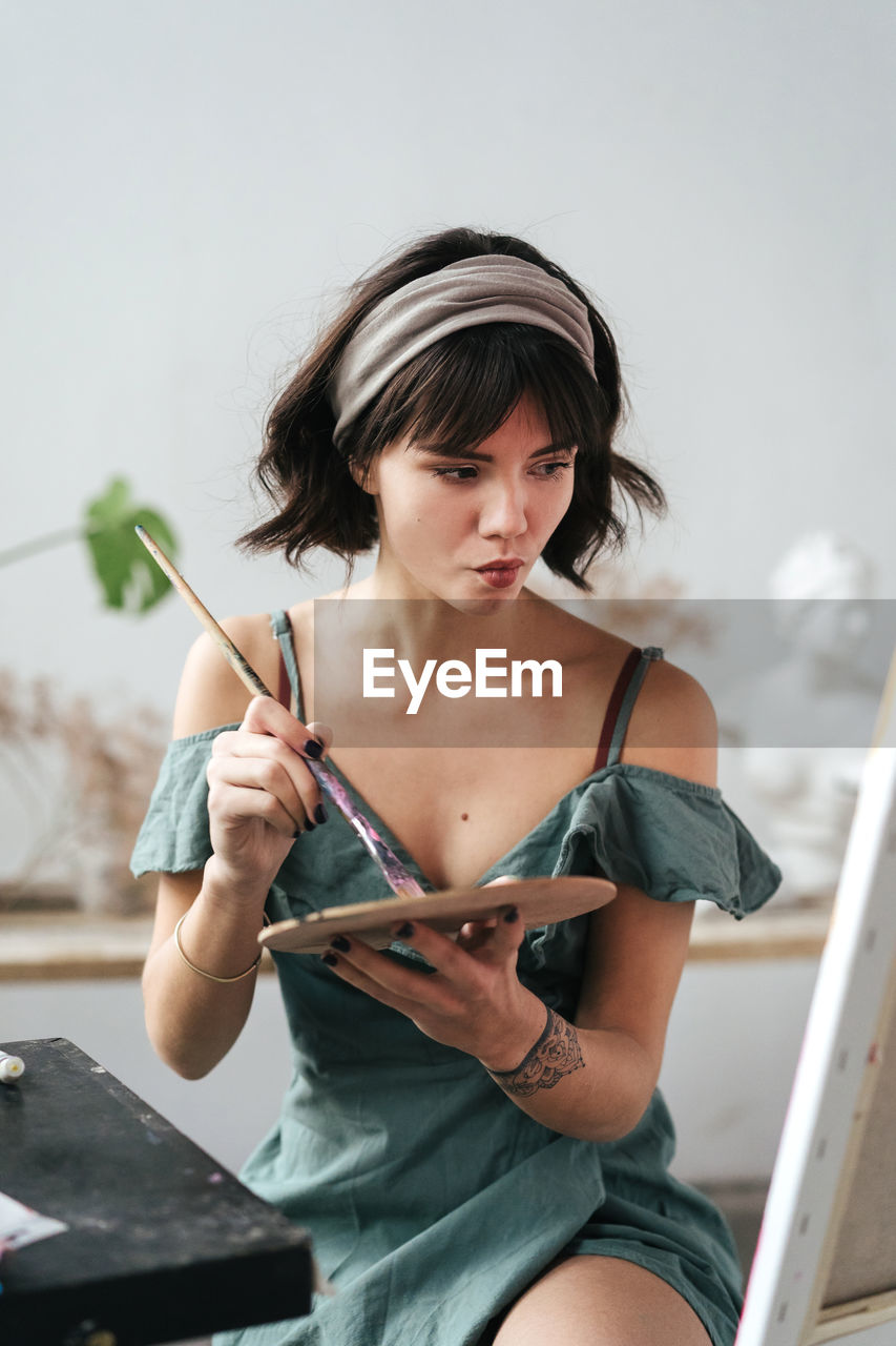 Female painter holding palette and paintbrush at art studio
