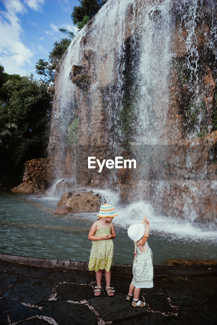 REAR VIEW OF PEOPLE STANDING ON WATERFALL