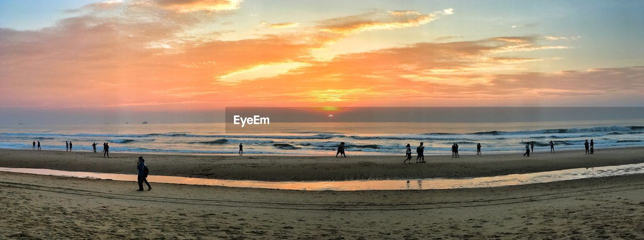 PEOPLE AT BEACH AGAINST SKY DURING SUNSET