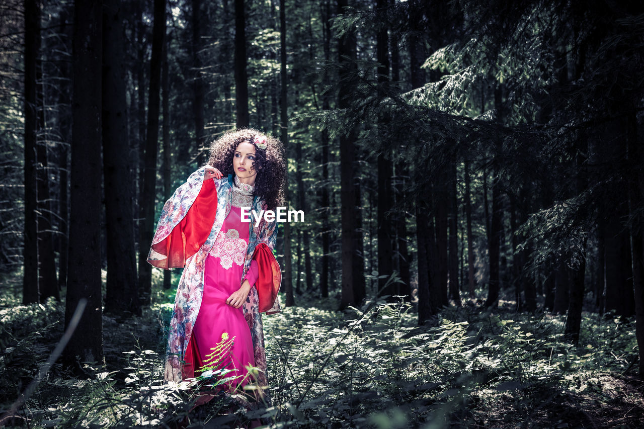 Beautiful mid adult woman wearing traditional clothing while standing in forest