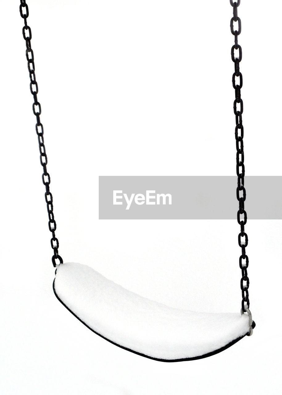 Close-up of empty swing against white background