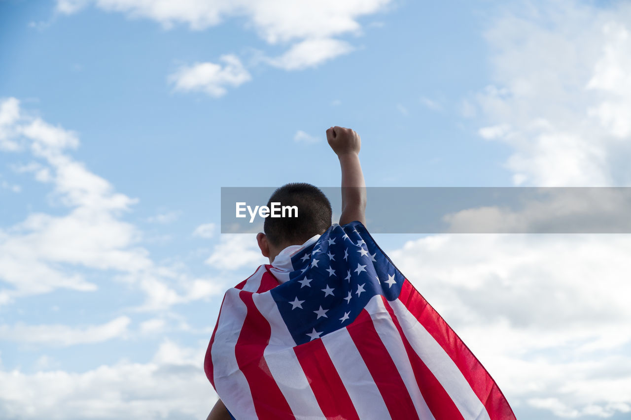 Low angle view of men flag against sky